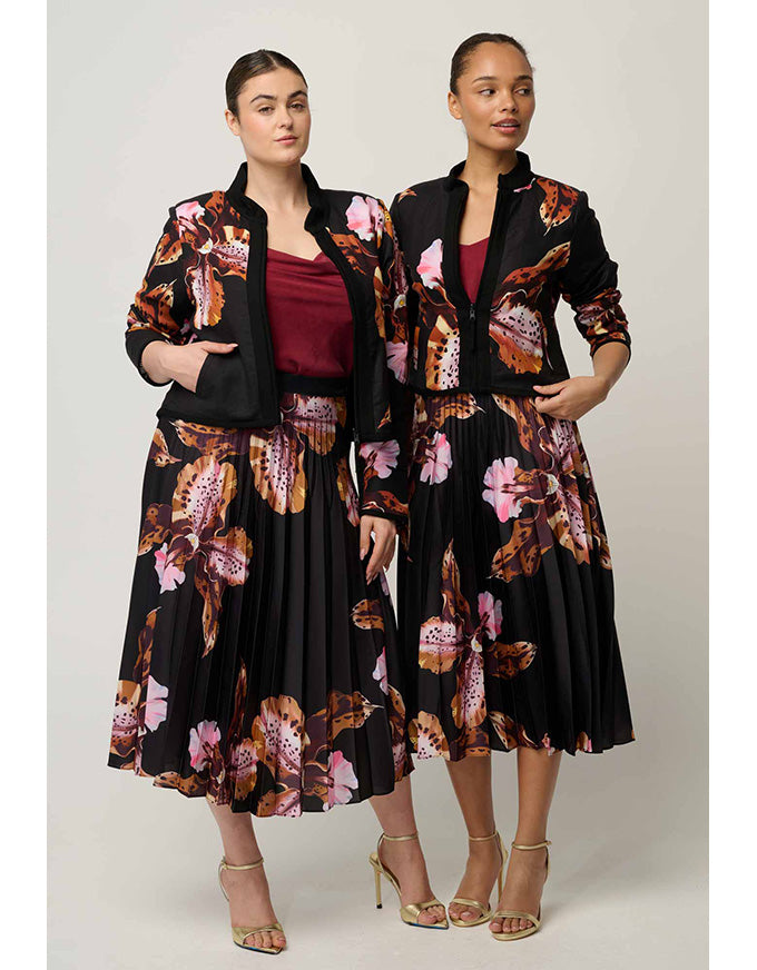 Two models wearing matching black floral midi dresses with wide lapels and black blazers, styled with a burgundy top and gold high heels against a light gray studio background.