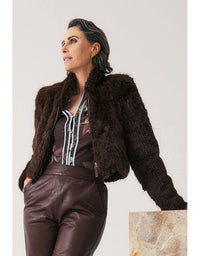 Woman wearing a brown fur jacket and leather pants on a light gray background