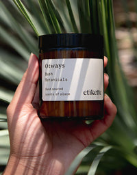 Hand holding a jar labeled 'Otways' with a plant in the background