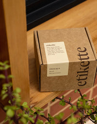 Brown box with 'etikette' branding on a wooden surface with plants in the foreground