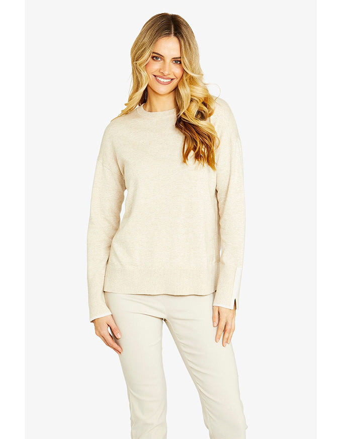 Woman wearing a beige sweater and pants on a white background