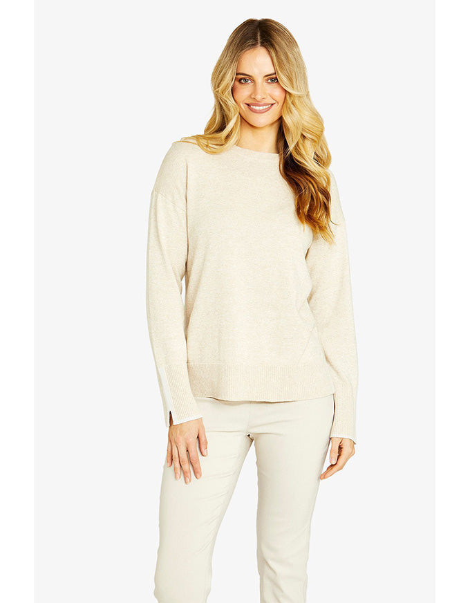 Woman wearing a beige sweater and pants on a white background