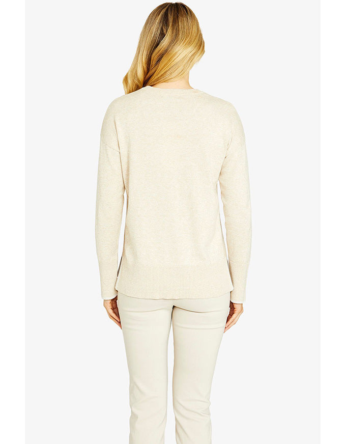 Person wearing a beige long-sleeve top and pants on a white background
