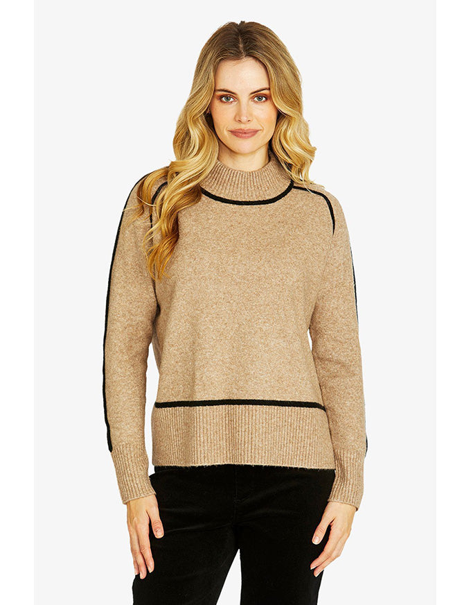 Woman wearing a beige sweater with black accents on a white background