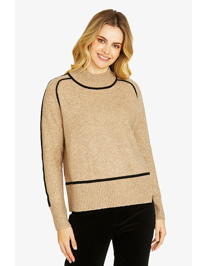 Woman wearing a beige sweater with black accents on a white background