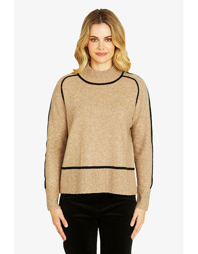 Woman wearing a beige sweater with black accents on a white background