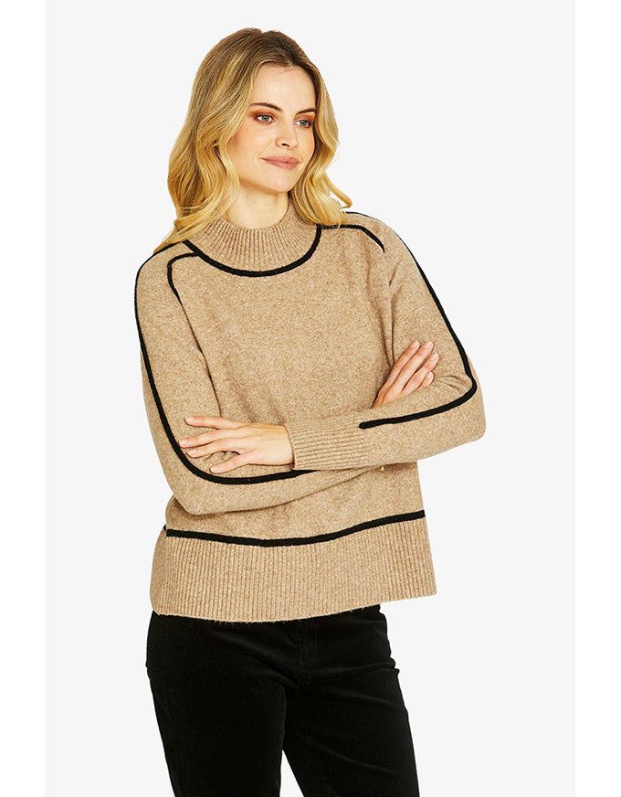 Woman wearing a beige sweater with black trim on a white background