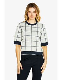 Woman wearing a checkered sweater with navy accents on a white background