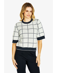 Woman wearing a grid-patterned top with black accents on a white background