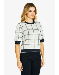 Woman wearing a checkered sweater with black trim on a white background