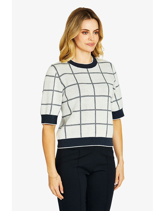 Woman wearing a checkered sweater with black trim on a white background