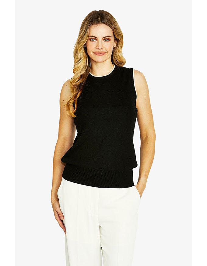Woman wearing a black sleeveless top and white pants on a white background