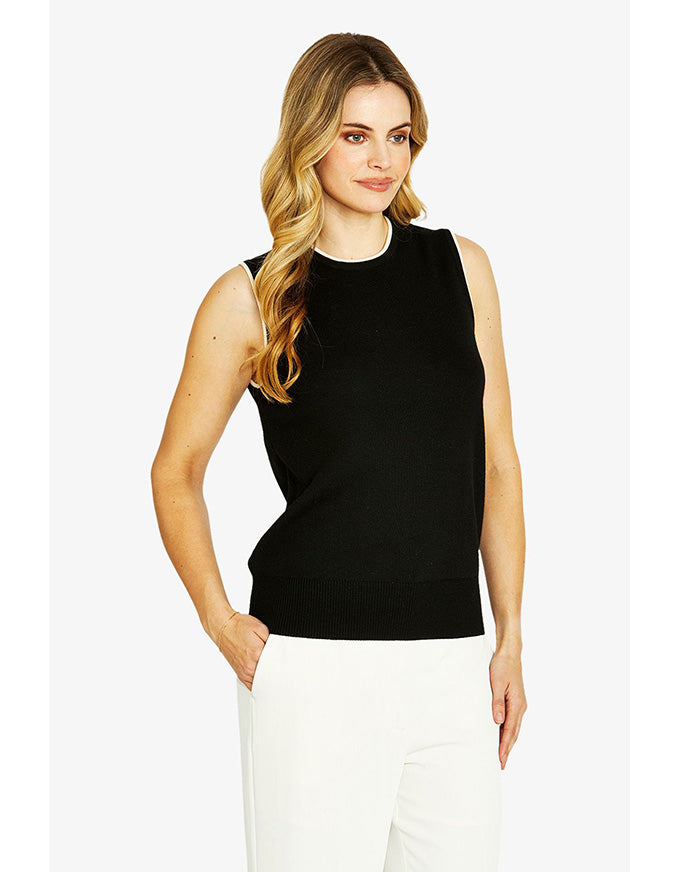 Woman wearing a black sleeveless top and white pants on a white background