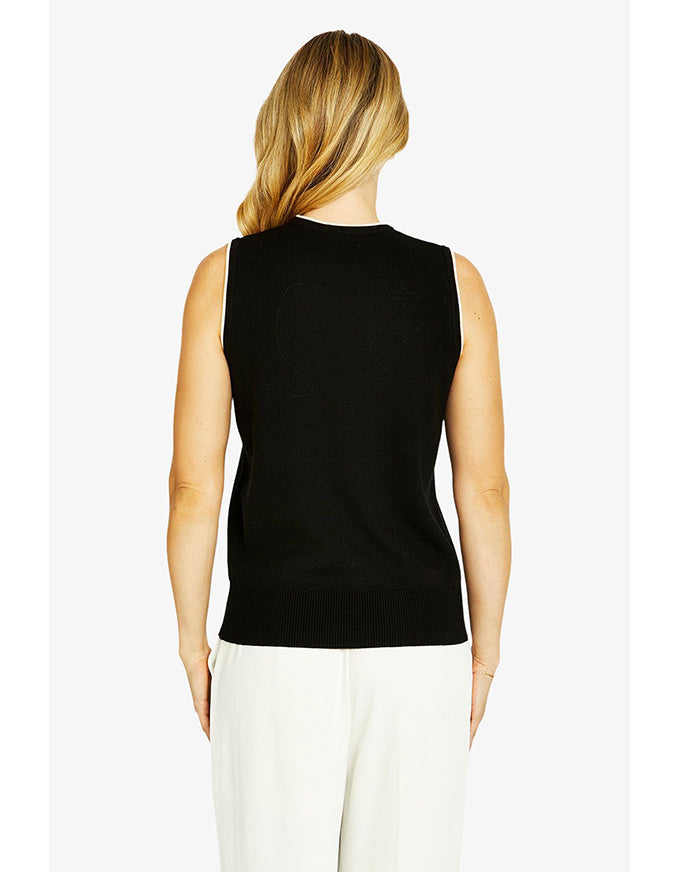 Woman wearing a black sleeveless top and white pants on a white background