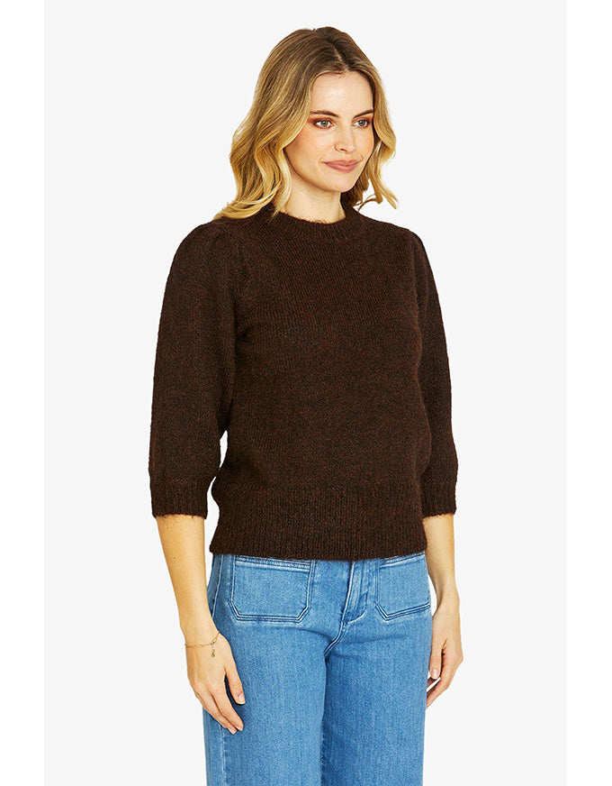 Woman wearing a brown sweater and blue jeans on a white background