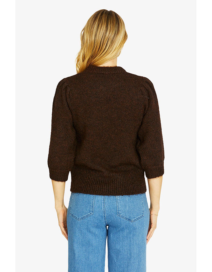 Person wearing a brown sweater and blue jeans on a white background
