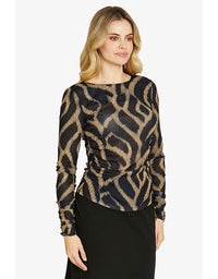Woman wearing a patterned black and gold top on a white background