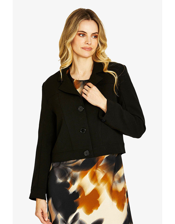 Woman wearing a black jacket over a tie-dye skirt on a white background