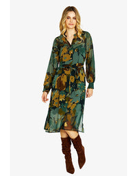 Woman wearing a green camouflage dress with brown knee-high boots on a white background