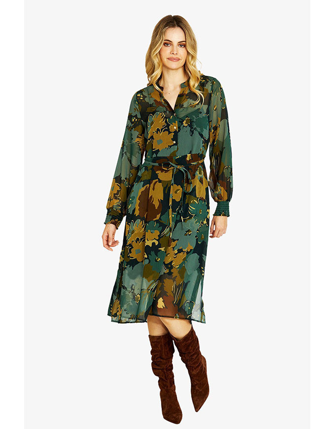 Woman wearing a green camouflage dress with brown knee-high boots on a white background