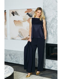 Woman in a navy outfit standing in a stylish room with marble walls and artwork.