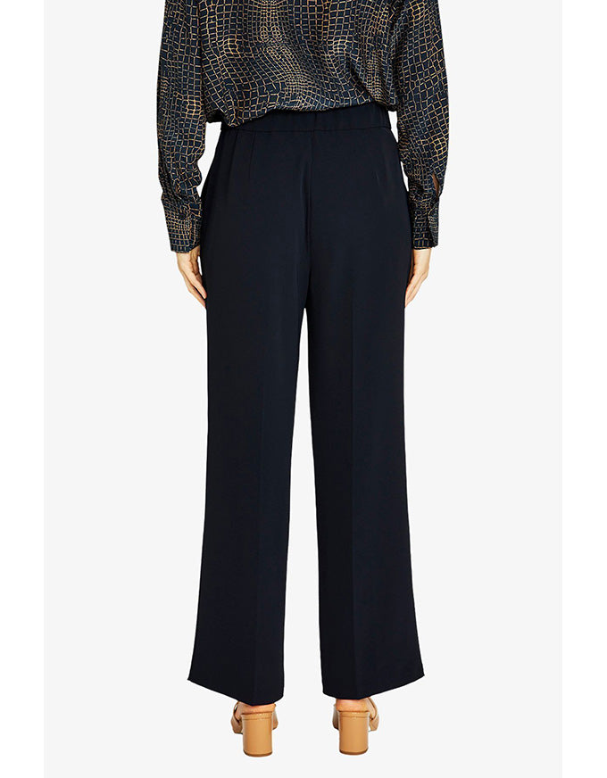 Person wearing a patterned top and black pants on a white background