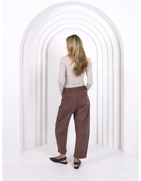 Person wearing brown pants standing in front of a white archway
