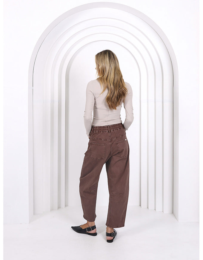 Person wearing brown pants standing in front of a white archway