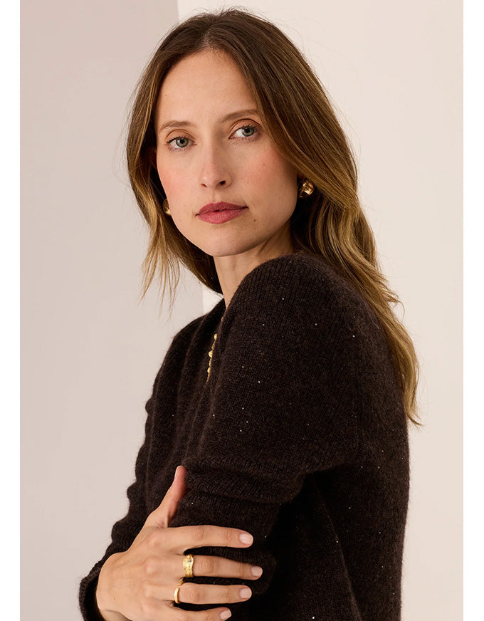 Woman wearing a dark brown sweater against a plain background