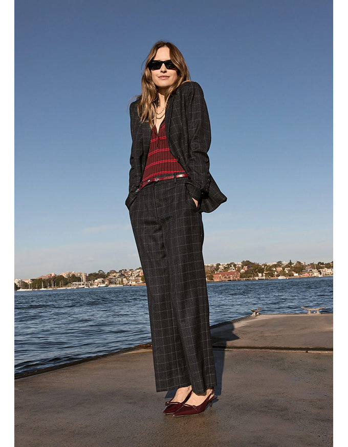 Woman in a suit standing by a waterfront with a clear blue sky.