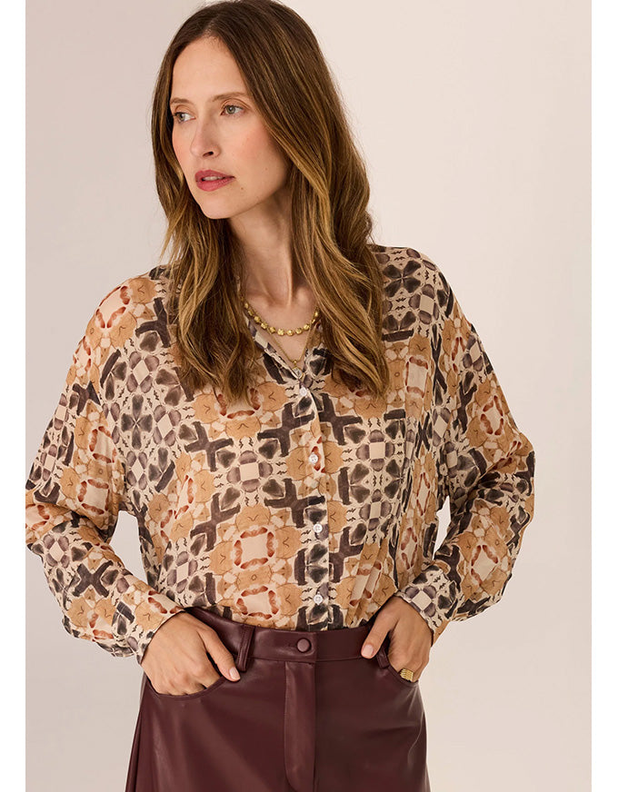 Woman wearing a patterned blouse with a plain background