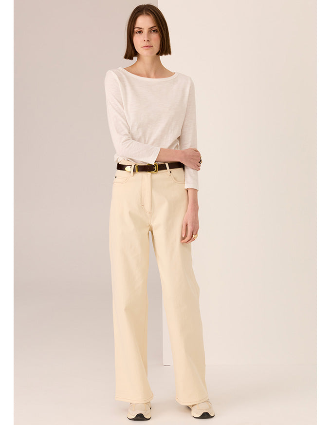 Woman wearing a white blouse and beige pants on a plain background
