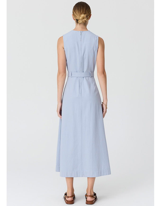 A woman viewed from the back wearing a sleeveless light blue midi dress with a matching waist tie, paired with brown sandals, against a light gray studio background.