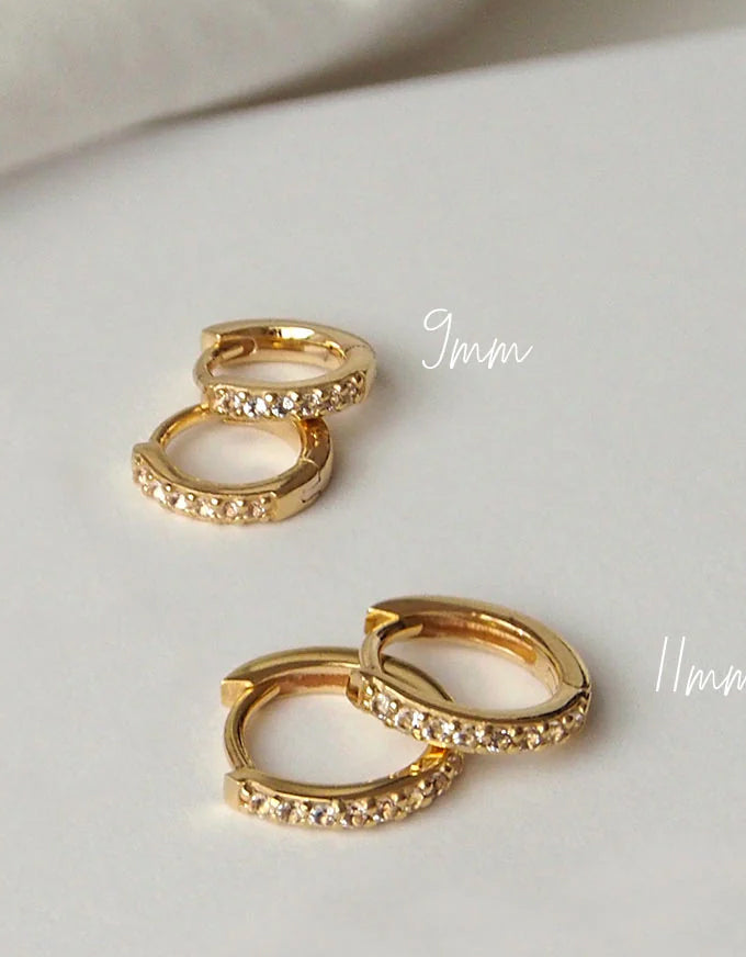 Gold hoop earrings with embedded stones on a white surface