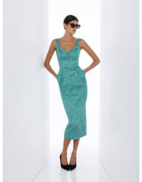 A woman modeling a sleeveless, fitted midi dress in a textured teal-green fabric, styled with black sunglasses and black heels, standing in a bright white studio setting.