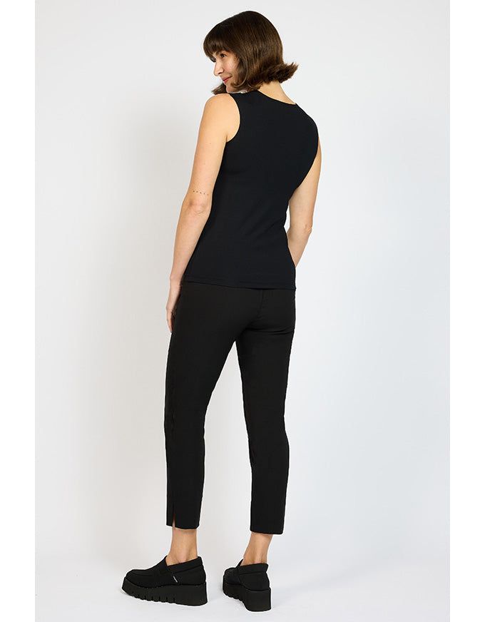 Woman wearing a black sleeveless top and black pants on a white background