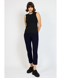 Woman wearing a black sleeveless top and navy pants on a white background