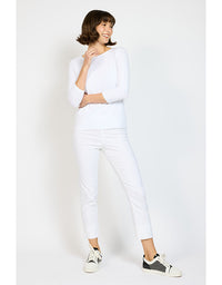 Woman wearing a white outfit with black sneakers on a plain background