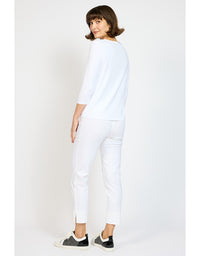 Woman wearing a white outfit with black sneakers on a plain background