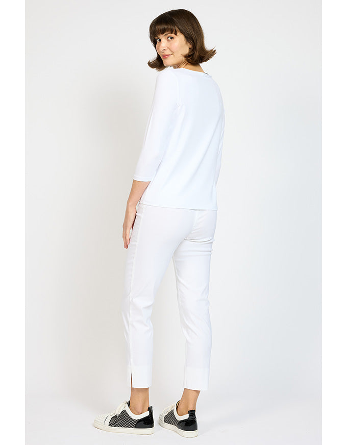 Woman wearing a white outfit with black sneakers on a plain background