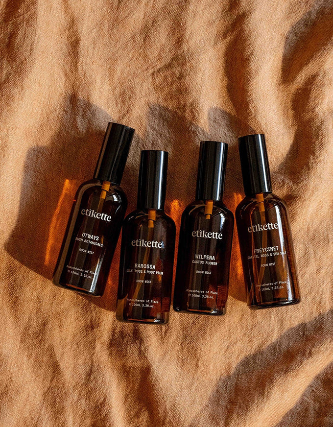 Four 'etikette' perfume bottles on a textured brown surface
