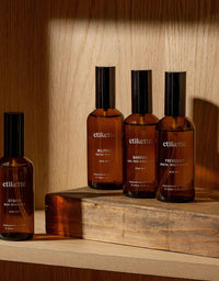 Four etikette skincare bottles on a wooden surface with a warm wooden background