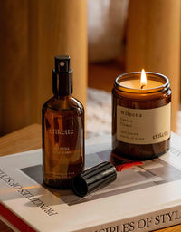 Brown bottle and lit candle labeled 'Wilpena' on a book with a blurred background