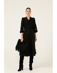 Woman wearing a black dress with feathered clutch and boots on a white background