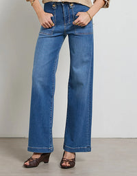 Person wearing blue jeans standing against a plain background