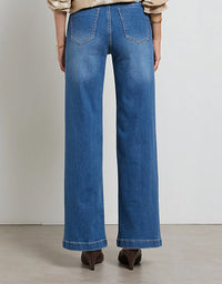 Person wearing blue jeans on a plain background
