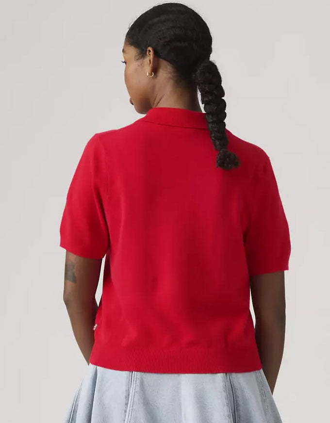 Person wearing a red polo shirt with a plain background
