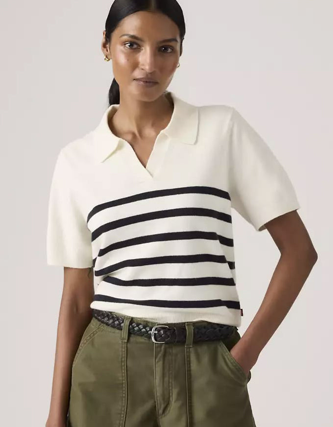 Woman wearing a white and black striped shirt with green pants on a light gray background. Super Soft Polo Sweater Isabella Stripes