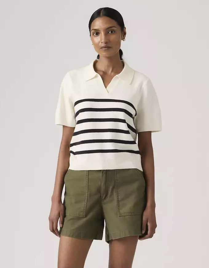Woman wearing a white and black striped shirt with green pants on a light gray background. Super Soft Polo Sweater Isabella Stripes