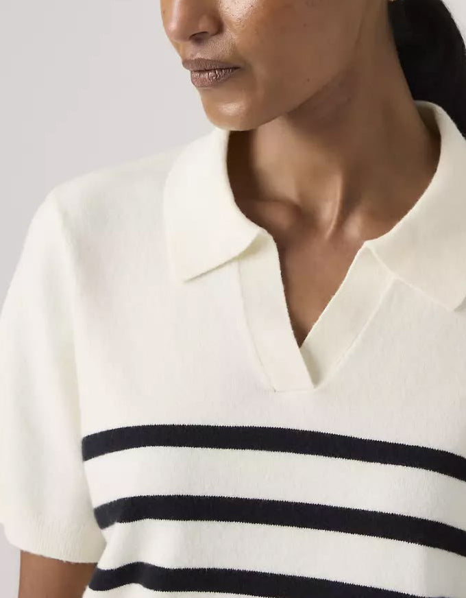 Close-up of a person wearing a white sweater with black stripes.